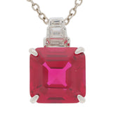 Emerald cut red ruby pendant with Moissanite accents in sterling silver setting, elegant jewelry piece.